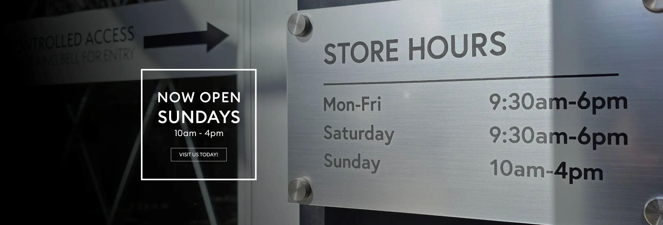 Glass storefront signage showing store hours: Monday to Friday and Saturday 9:30am–6pm, Sunday 10am–4pm, with an additional “Now open Sundays” notice.